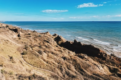 Under the blue sky during the day brown rock which is near the sea
